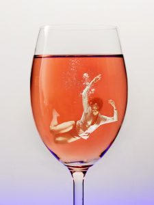 person swimming in a glass of alcohol