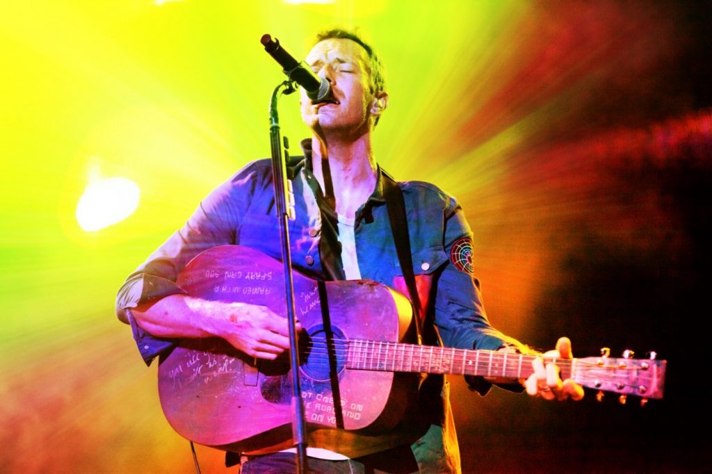 Chris Martin, lead singer of Coldplay, playing guitar on stage in Austin, Texas